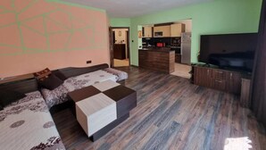 A modern living room with a sofa, a coffee table, and a TV. There is a kitchen area with a microwave and a refrigerator. - Apartment Lozenets, Sofia, Bulgaria (Sofia)