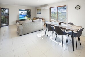Un salon moderne comprenant un canapé, un téléviseur, une table à manger et des chaises.