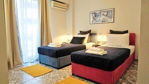 A hotel room with two beds, a window with curtains, an air conditioner, and a framed picture on the wall. - A few Steps from Syntagma and Plaka (Athens)