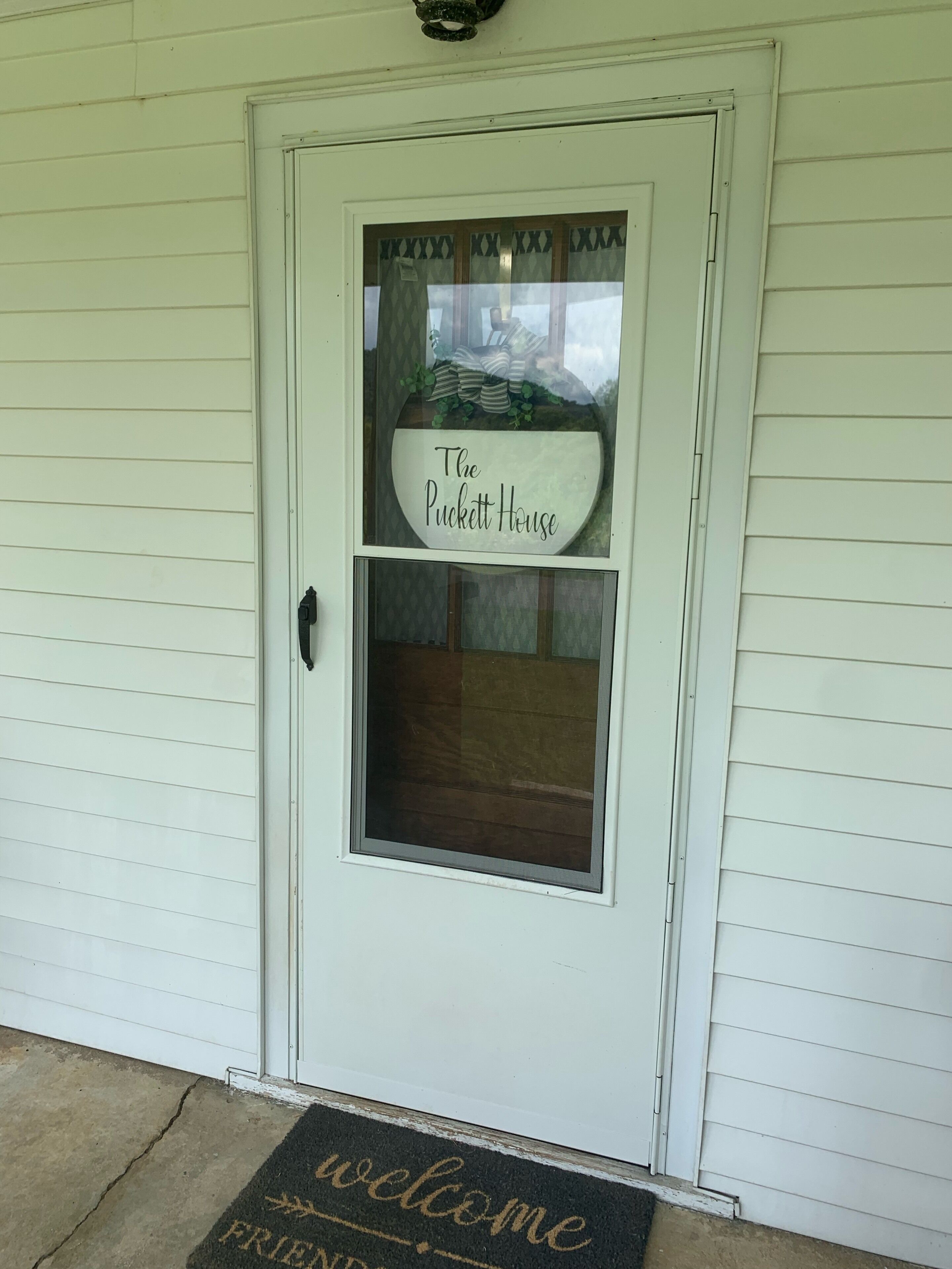 Une porte blanche avec une enseigne indiquant « The Puckett House » au-dessus d’une fenêtre.