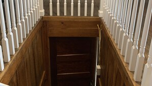 Un escalier en bois, avec des balustrades blanches, mène à une porte en bois sombre.