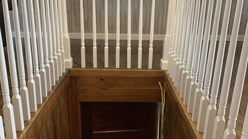 Un escalier en bois, avec des balustrades blanches, mène à une porte en bois sombre.
