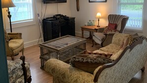 Un salon avec un canapé vintage, une table basse, un téléviseur et une cheminée.
