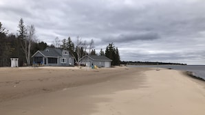 A beach with a row of houses, a volleyball net, and a clear view of the water.
