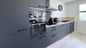 A modern kitchen with a Bosch stove, grey cabinetry, and a window with a view. - Comfortable Chalet - View of Lake Aiguebelette (La Motte-Servolex)