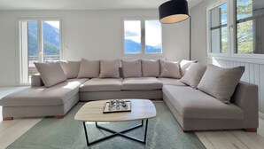 A modern living room with a sectional sofa, a coffee table, and a pendant light. - Comfortable Chalet - View of Lake Aiguebelette (La Motte-Servolex)