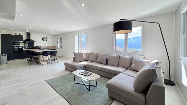 A modern living room with a sectional sofa, a coffee table, and a dining area with chairs. - Comfortable Chalet - View of Lake Aiguebelette (La Motte-Servolex)