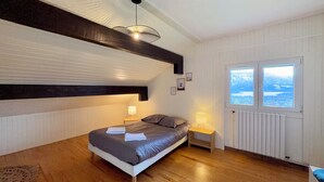 A bedroom with a bed, bedside tables, a window, and a view. - Comfortable Chalet - View of Lake Aiguebelette (La Motte-Servolex)