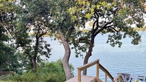 Una terraza de madera junto a un lago, con un bote amarrado cerca.