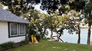 Una casa con patio césped, terraza de madera y vista al lago.