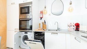 A compact kitchen with a microwave, oven, dishwasher, and a sink.