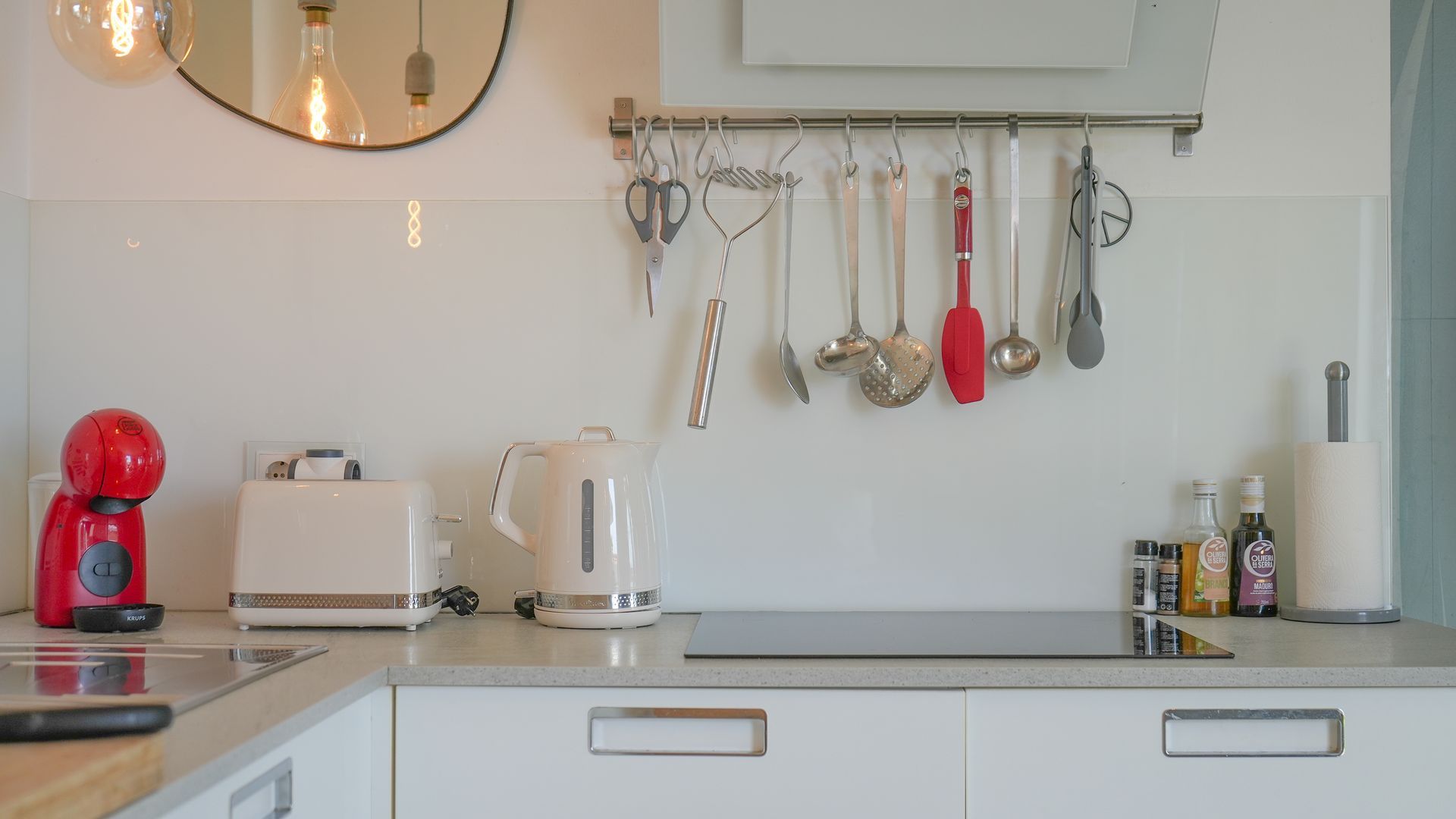 A kitchen with a coffee maker, toaster, kettle, and hanging utensils.