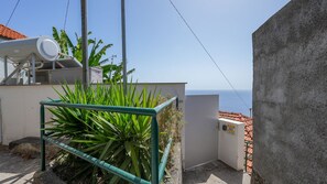 A rooftop with a telescope, a concrete wall, and a view of the sea.