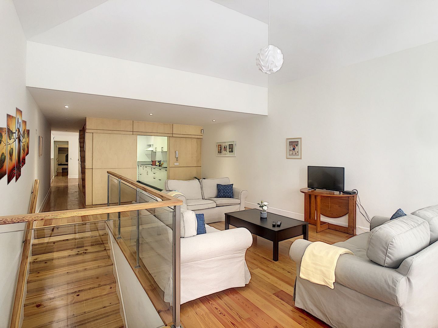 Una sala de estar moderna con una escalera, un sofá, una mesa de centro y un televisor.
