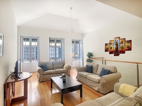 A spacious living room with two sofas, a coffee table, and a TV stand.