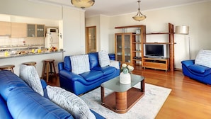 A living room with a blue sofa set, a coffee table, a TV, and a wooden cabinet. - Gemini Apartment by LovelyStay (Funchal)