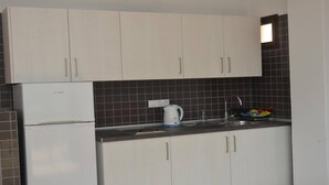 A compact kitchen with white cabinets, a white refrigerator, a kettle, and a sink with a faucet. - Apt. El Molino 2B  (Valle Gran Rey)