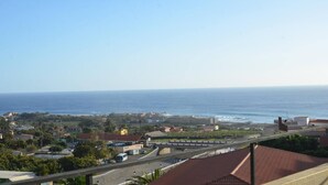 Une ville côtière avec vue sur la mer, des bâtiments et une route où circulent des véhicules.