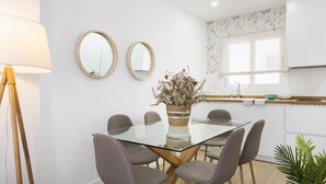 A modern kitchen with white cabinets, a glass dining table, and a potted plant. - Genteel Home Juan Rabadan I (Seville)