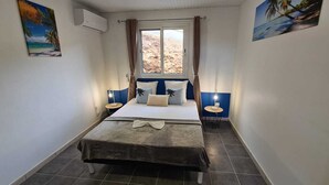 Ein Schlafzimmer mit einem Bett, zwei Nachttischen, einem Fenster mit Vorhängen und Wandbildern.
