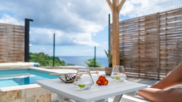 Ein Tisch am Pool mit einem Glas, einer Schale und einer Blume.
