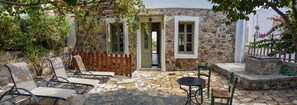A stone building with a wooden fence, a stone patio with outdoor seating, and a view of the surrounding area.