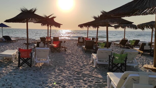 A beach with rows of sun loungers and thatched umbrellas. - Stone House Kleio Kos  (Αντιμάχεια)
