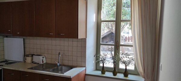 Eine Küche mit braunen Schränken, einer gefliesten Spritzschutzwand, einem Spülbecken, einem Toaster und drei Vasen auf der Fensterbank.