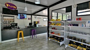 A modern retail space with a 'Welcome' sign, a counter with wine bottles, and shelves stocked with various products. - SleepOver Beitbridge (Musina)