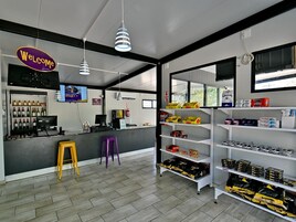 Um espaço comercial moderno com um letreiro que diz 'Welcome', um balcão com garrafas de vinho e prateleiras repletas de diversos produtos.