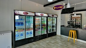 A clean, modern interior with a 'Welcome' sign, a bar area, and multiple beverage dispensers. - SleepOver Beitbridge (Musina)