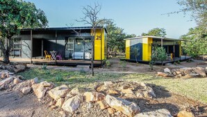 Two yellow and black cabins with outdoor seating, surrounded by rocks and sparse vegetation. - SleepOver Beitbridge (Musina)