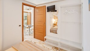 A bedroom with a bed, a wardrobe, a TV, and a mirror. - Tiny House 21 Bright Aparment (Polignano a Mare)