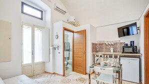 A compact living space with a kitchenette, a dining area, and a bathroom. - Tiny House 21 Bright Aparment (Polignano a Mare)