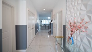 A modern hallway with a marble floor, white doors, and a decorative wall with geometric patterns.