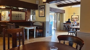 A restaurant interior with wooden furniture, a bar area, and framed pictures on the walls. - The Cheney Arms (Leicester)