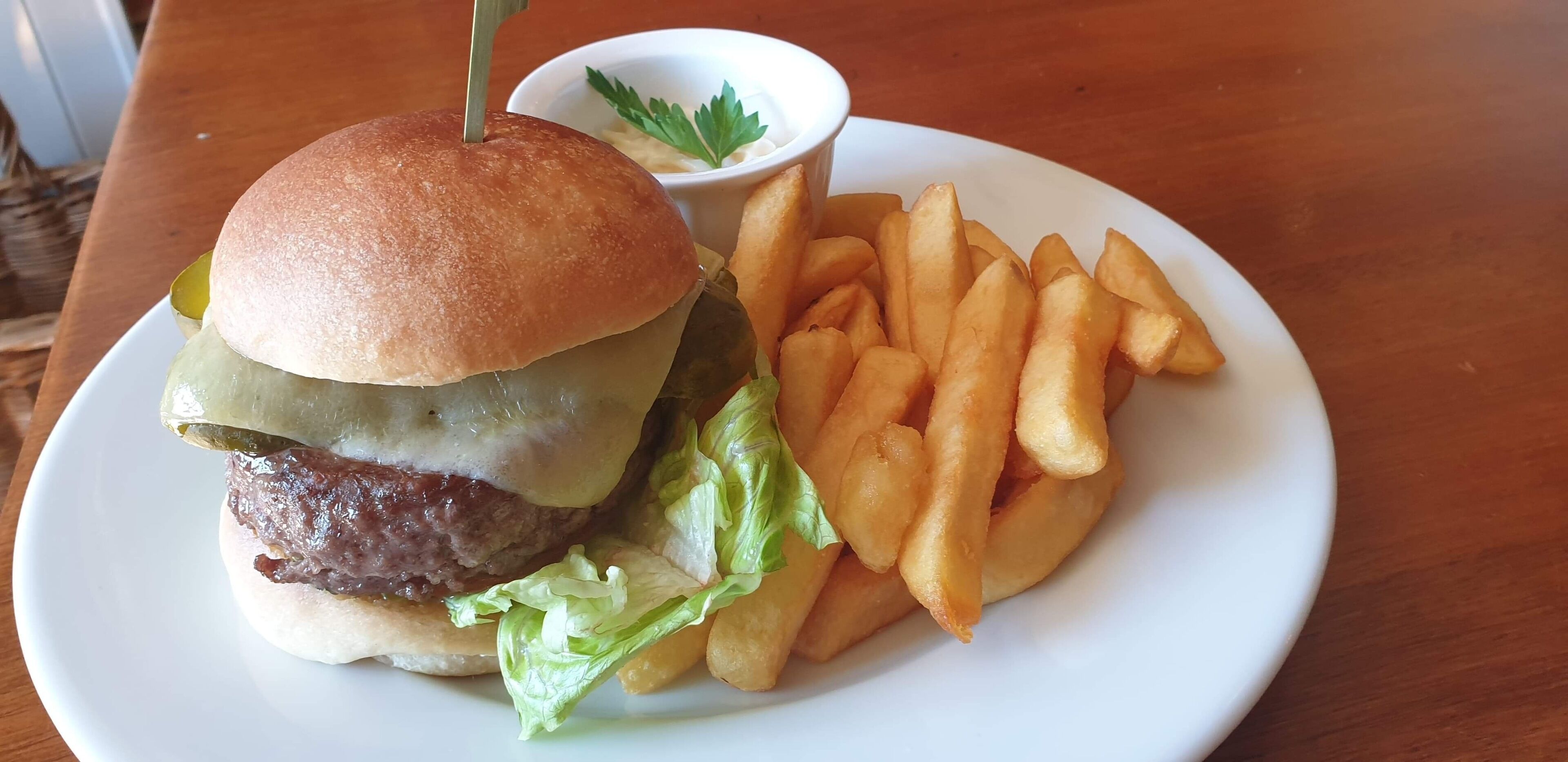Un plato con una hamburguesa, papas fritas y un recipiente pequeño de salsa.