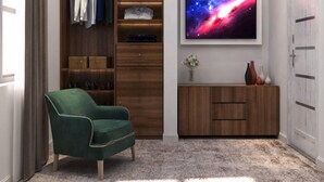 Quarto moderno com poltrona verde, armário de madeira, penteadeira com espelho e uma TV grande exibindo uma cena espacial.