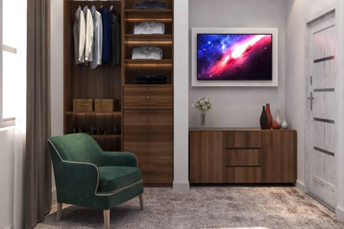 A modern room with a green armchair, a wooden wardrobe, a vanity with a mirror, and a large TV displaying a space scene.