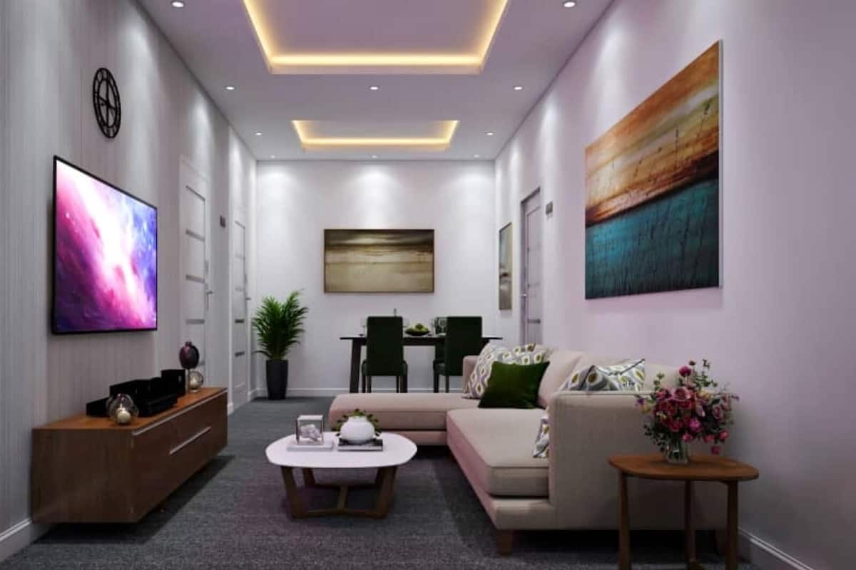 A modern living room with a flat-screen TV, a sofa, a coffee table, and a small table with flowers.