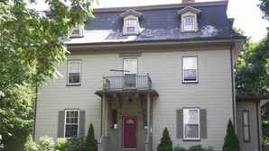 A two-story house with a front porch, a red door, and a small balcony. - Spacious Egleston Sq 3 Bedroom, Dog Friendly (Boston)