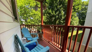 A covered porch with two blue Adirondack chairs, a small table, and hanging planters. - Spacious Egleston Sq 3 Bedroom, Dog Friendly (Boston)