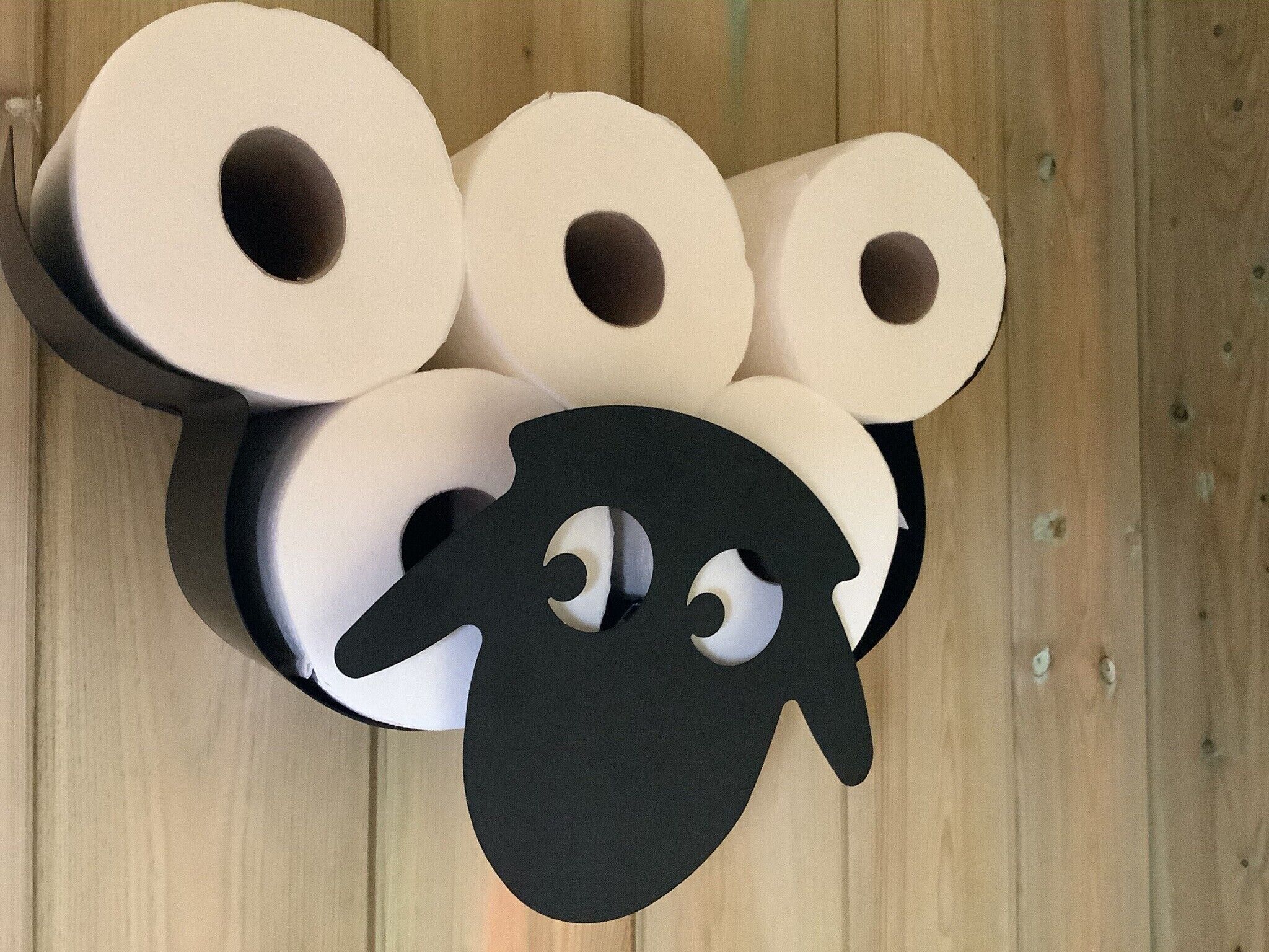 A top-down view of a wooden floor with several rolls of toilet paper arranged in a cluster.