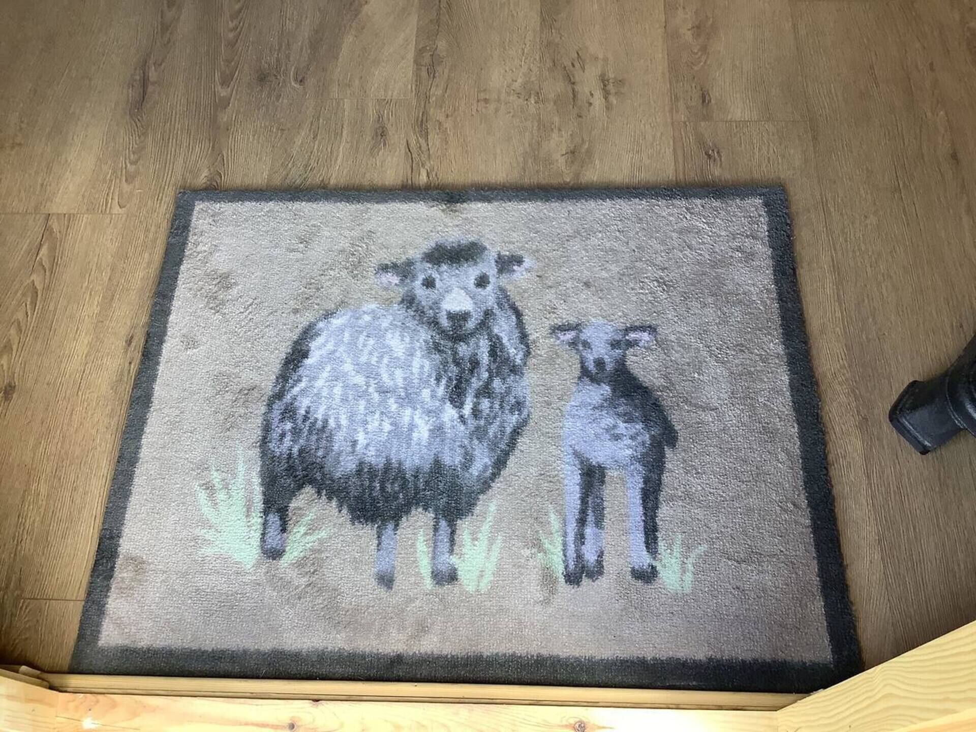 En dørmåtte med et design af får og lam.