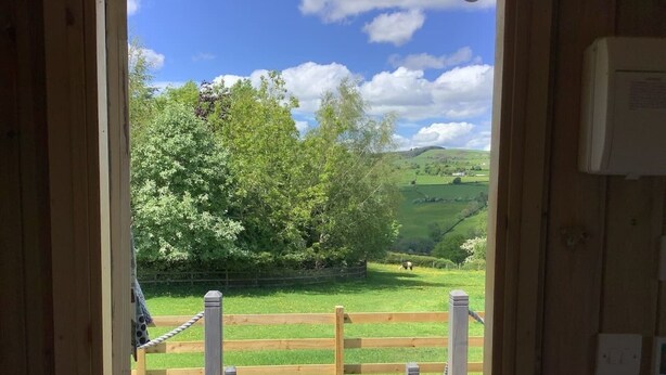 A wooden deck with a view of a green field and trees. - The Shepherds Hut at Hafoty Boeth (Corwen)