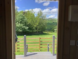 A wooden deck with a view of a green field and trees. - The Shepherds Hut at Hafoty Boeth (Corwen)