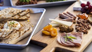 Una tabla de madera con diversos quesos, embutidos y frutas.