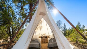 Una tienda tipi con dos camas, una mesita y un sistema de sonido.