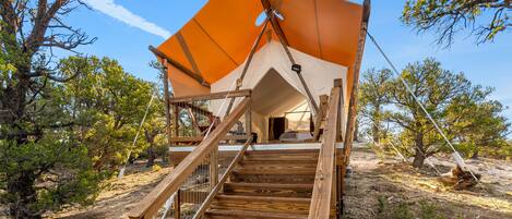 A wooden staircase leading to a tent-like structure with a large orange canopy.
