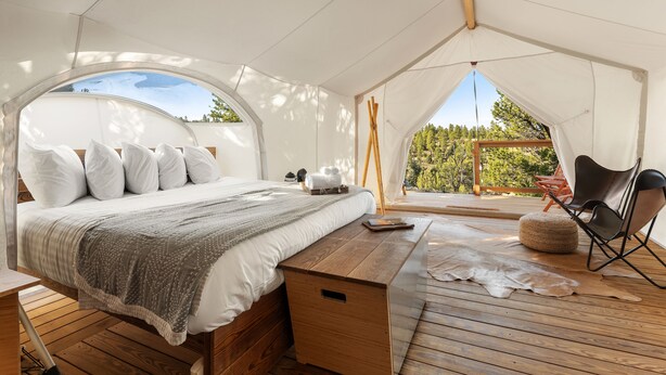Una habitación con carpa, una cama, un banco de madera y una silla.
